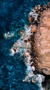 A stunning aerial shot showcasing waves crashing on a rocky coast in İzmir, Türkiye.