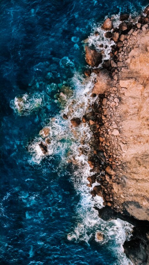 Free A stunning aerial shot showcasing waves crashing on a rocky coast in İzmir, Türkiye. Stock Photo