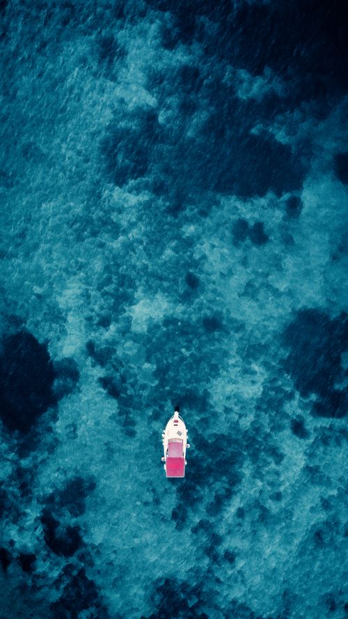 Free Aerial photo of a boat with red canopy floating on the clear blue waters of İzmir, Türkiye. Stock Photo