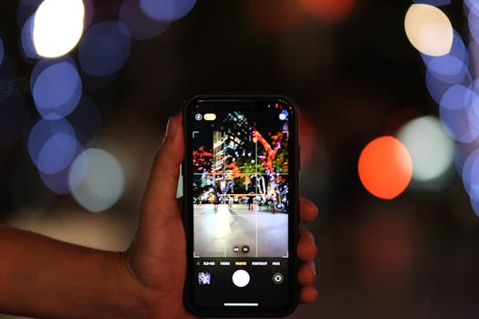 Close-up of a smartphone capturing a vibrant city scene with colorful bokeh lights at night.
