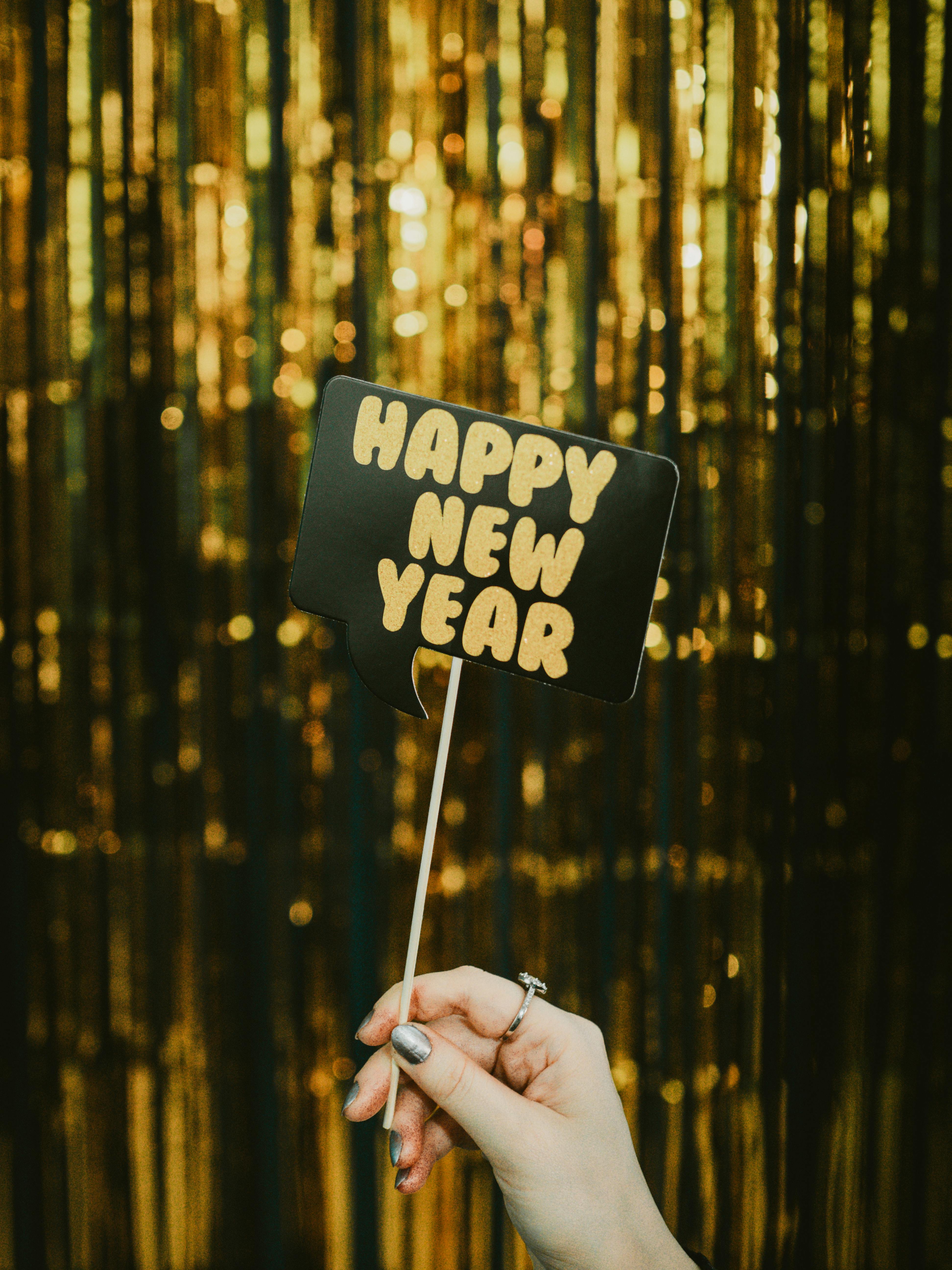 happy new year speech bubble on a stick with a golden curtain in the background