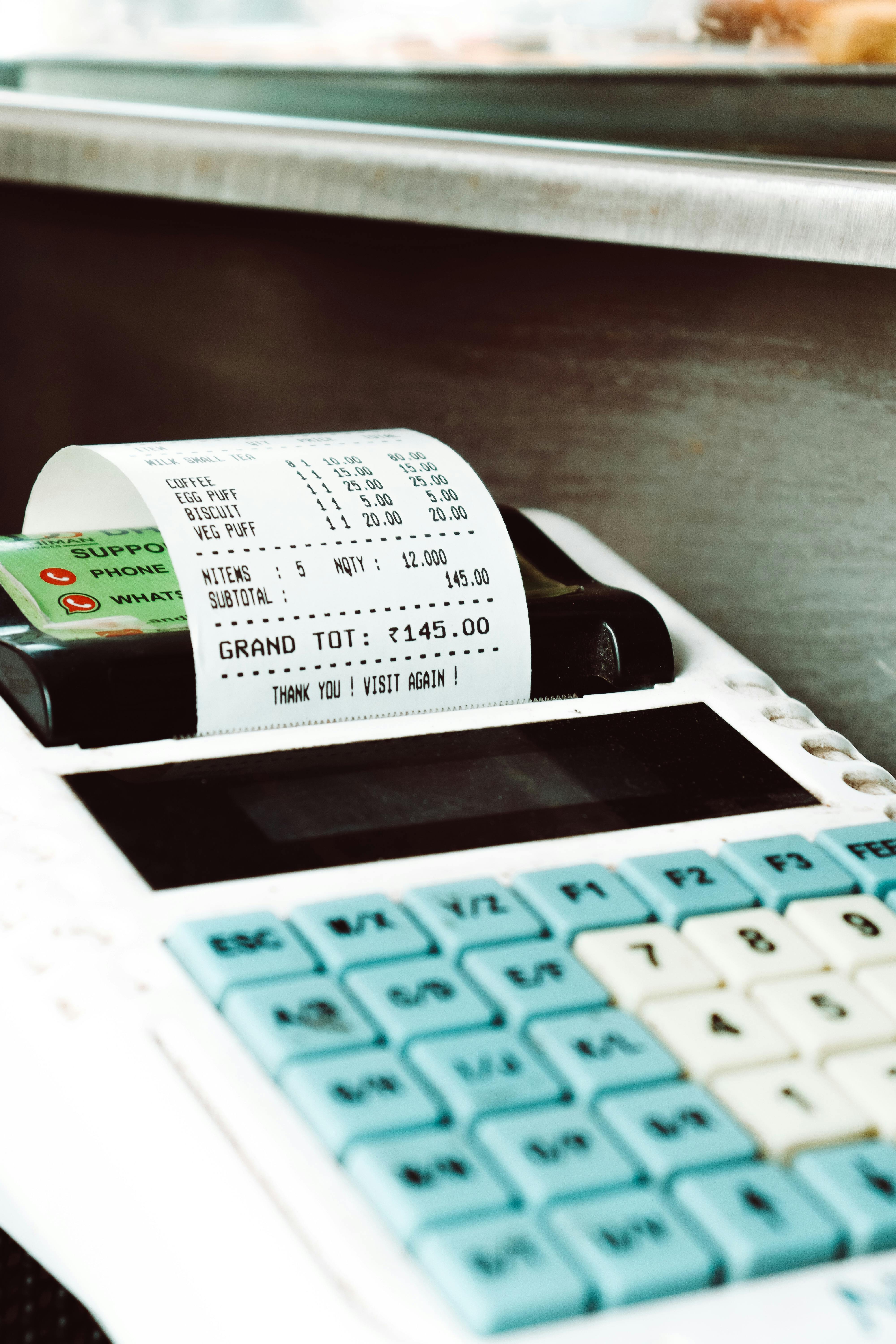 Close-up shot of a cash register printing a receipt with a card nearby, in a retail store.