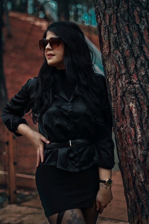 Woman in Sunglasses and Black Clothes Standing by Tree