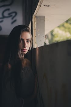 在昏暗的废弃建筑里，墙上靠着一个女人，她的肖像显得喜怒无常