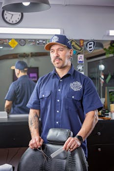 A skilled barber with a mustache standing in a modern barbershop, ready for work.