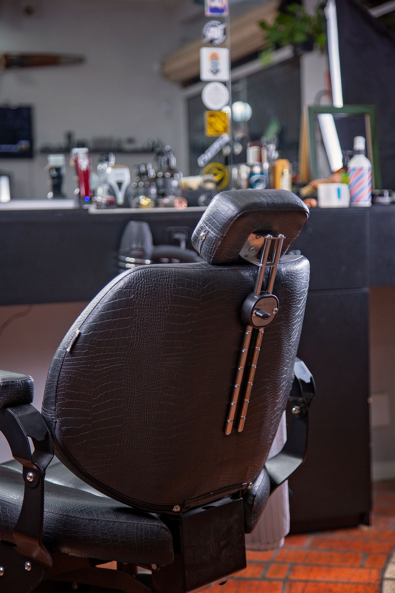 Fauteuil de coiffeur en cuir sombre, espace de soin équipé avec miroir et éclairage doux