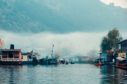 Free Peaceful boathouses on misty Dal Lake in Jammu, surrounded by fog and mountains. Stock Photo