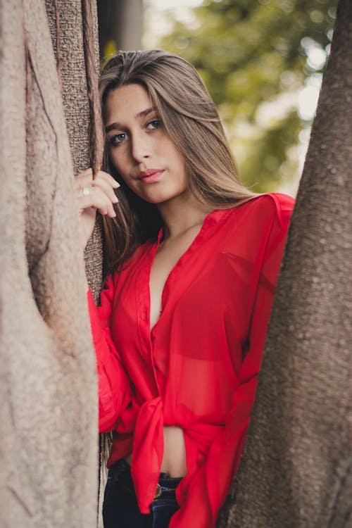 Woman Wearing Red Long-sleeved Shirt Leaning on Brown Tree