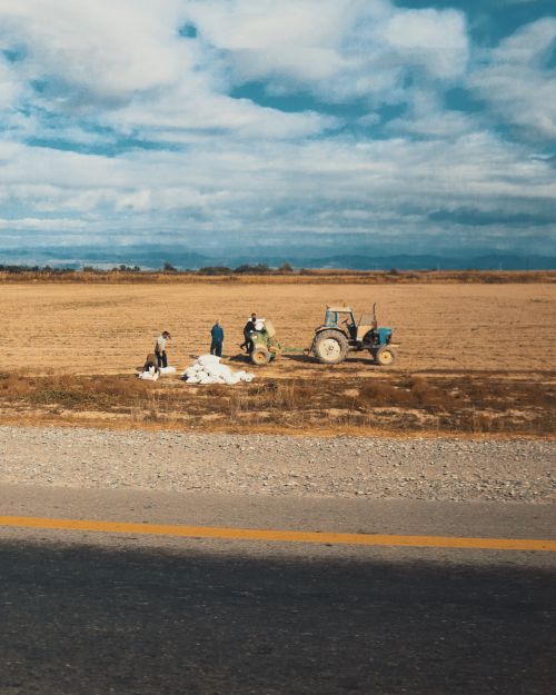 Free Farmers and a tractor working in a rural field in Azerbaijan, capturing agricultural life. Stock Photo