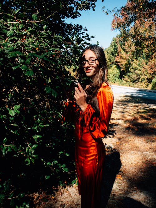 Young woman wearing a red dress posing by a tree 