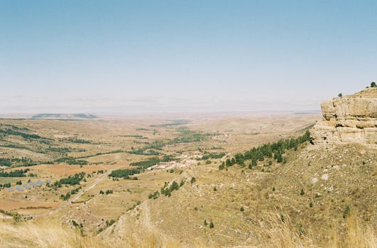 A vast aerial view of a dry landscape with clear blue skies and scattered greenery.