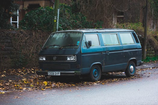 A classic Volkswagen van parked on a leaf-covered street in an urban setting, capturing a nostalgic vibe.