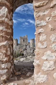 View of Rocca Calascio castle through a stone archway in Abruzzo, Italy.