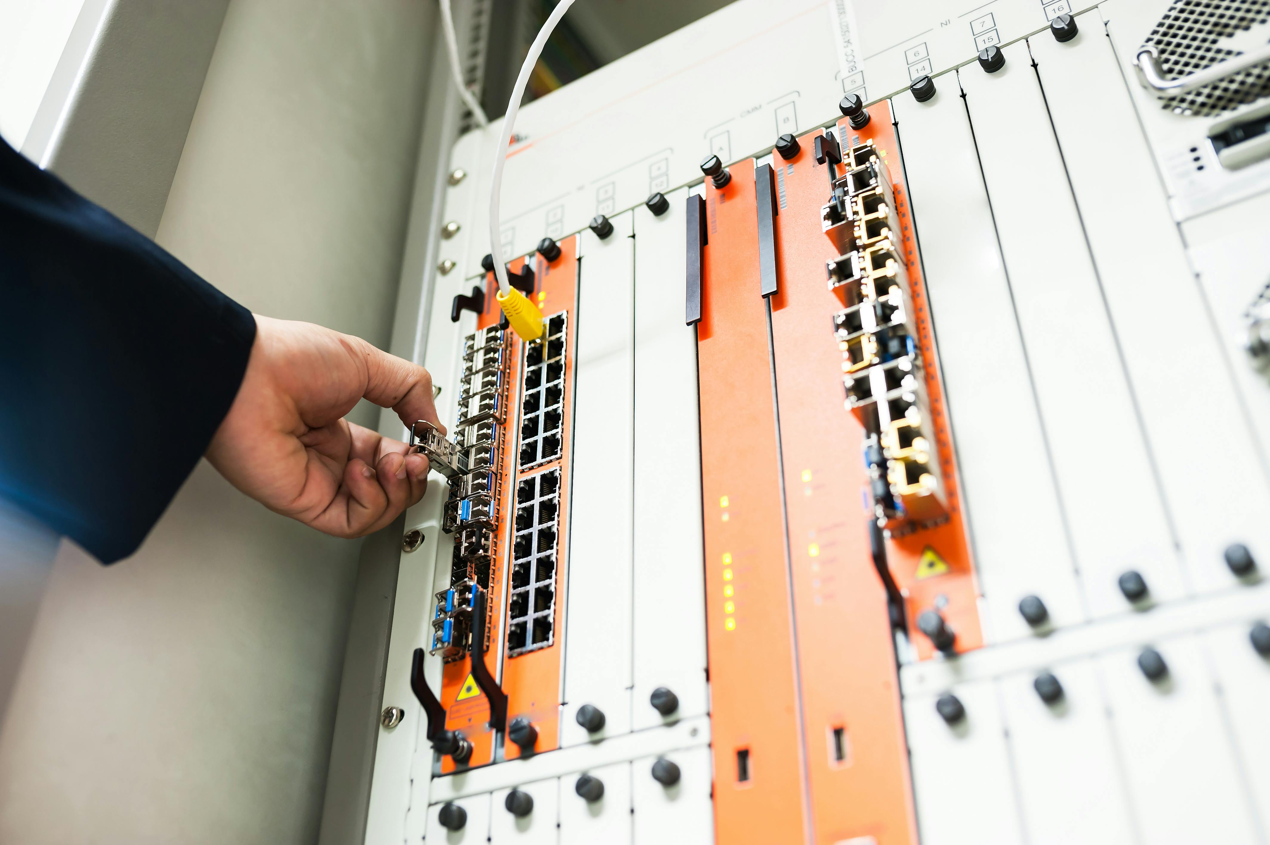 Close-up of a hand adjusting network equipment in a data center.