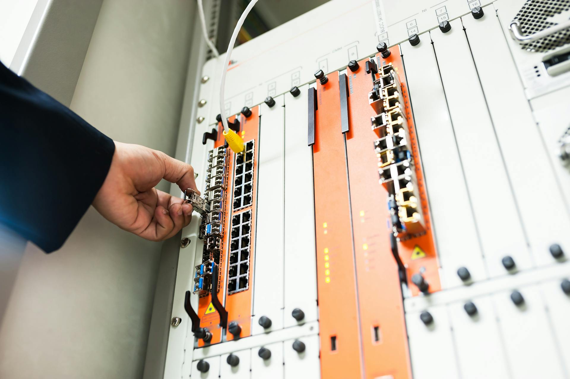 Close-up of a hand adjusting network equipment in a data center.