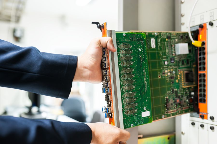 A technician inserts a circuit board into a server rack, illustrating technology and connectivity.