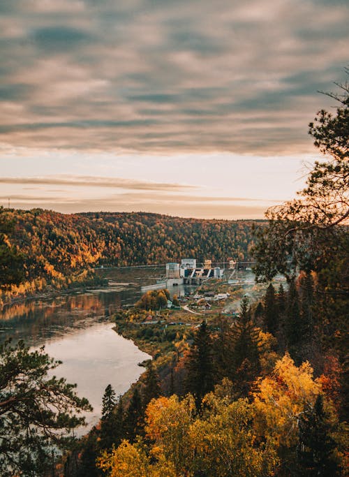 Dam on the River Among the Autumn Forest at Sunset