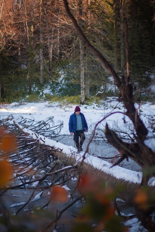 Man Walking on a Tree Log across the Water in Winter 