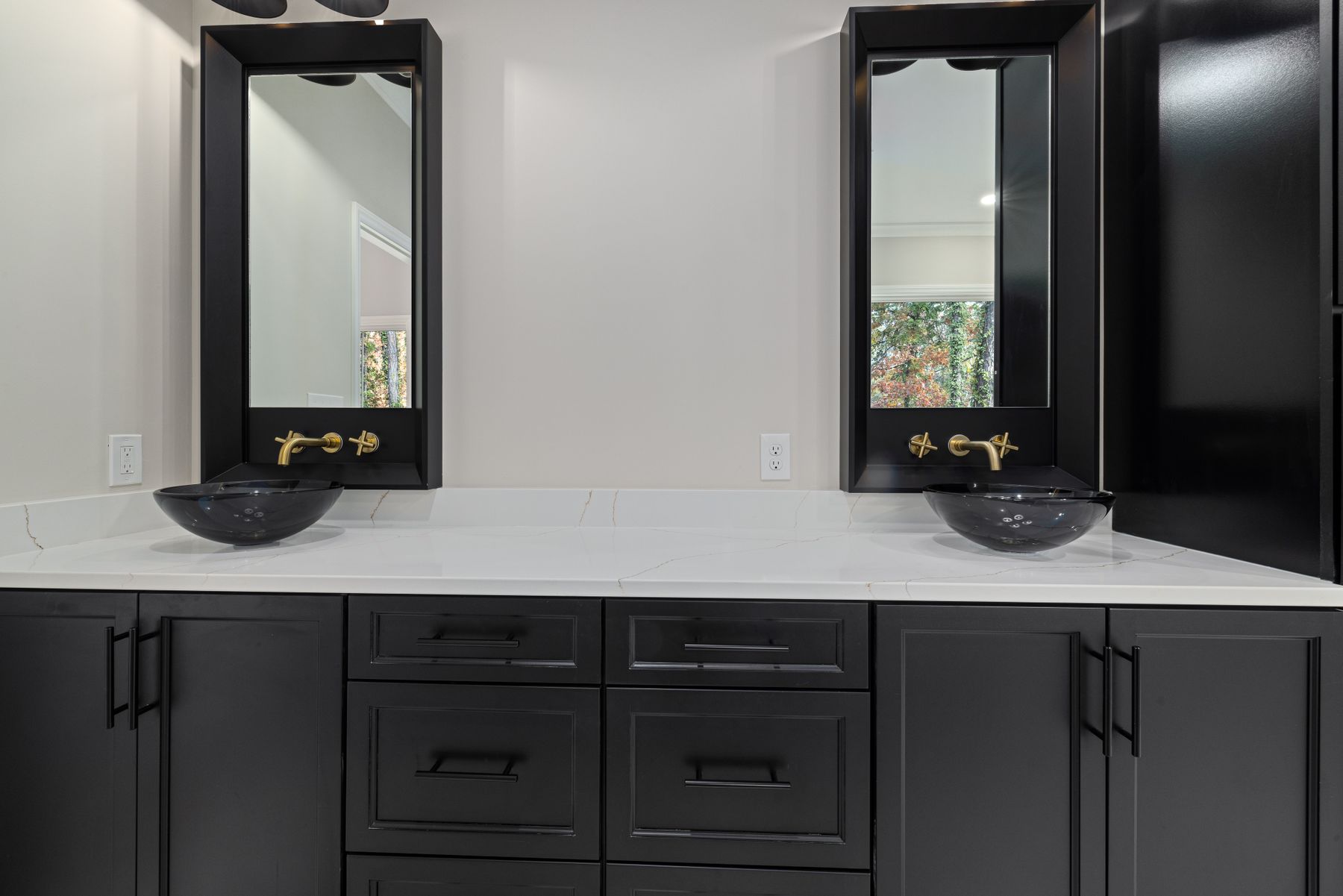 Bathroom with black cabinets, vessel sinks, large mirrors and gold hardware