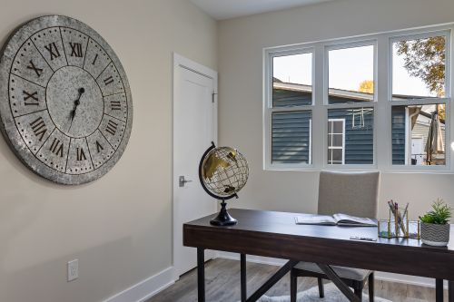 Free Spacious home office with a large vintage clock and globe, perfect for work and study. Stock Photo