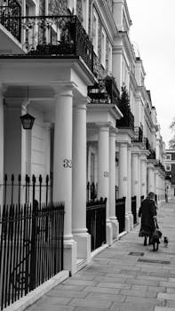 Black and white photograph capturing a woman walking her dog along elegant Edinburgh townhouses.