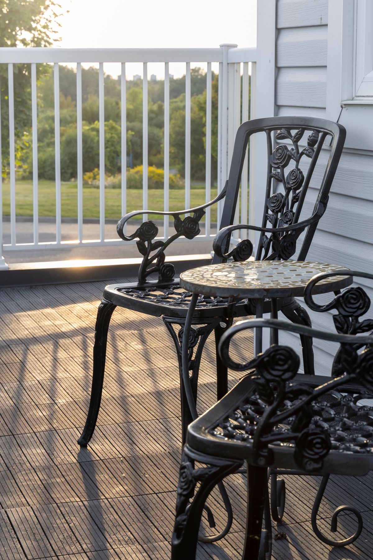 Beautiful cast iron chairs and table on a sunny porch, perfect for relaxation and enjoying nature. Stock Photo.