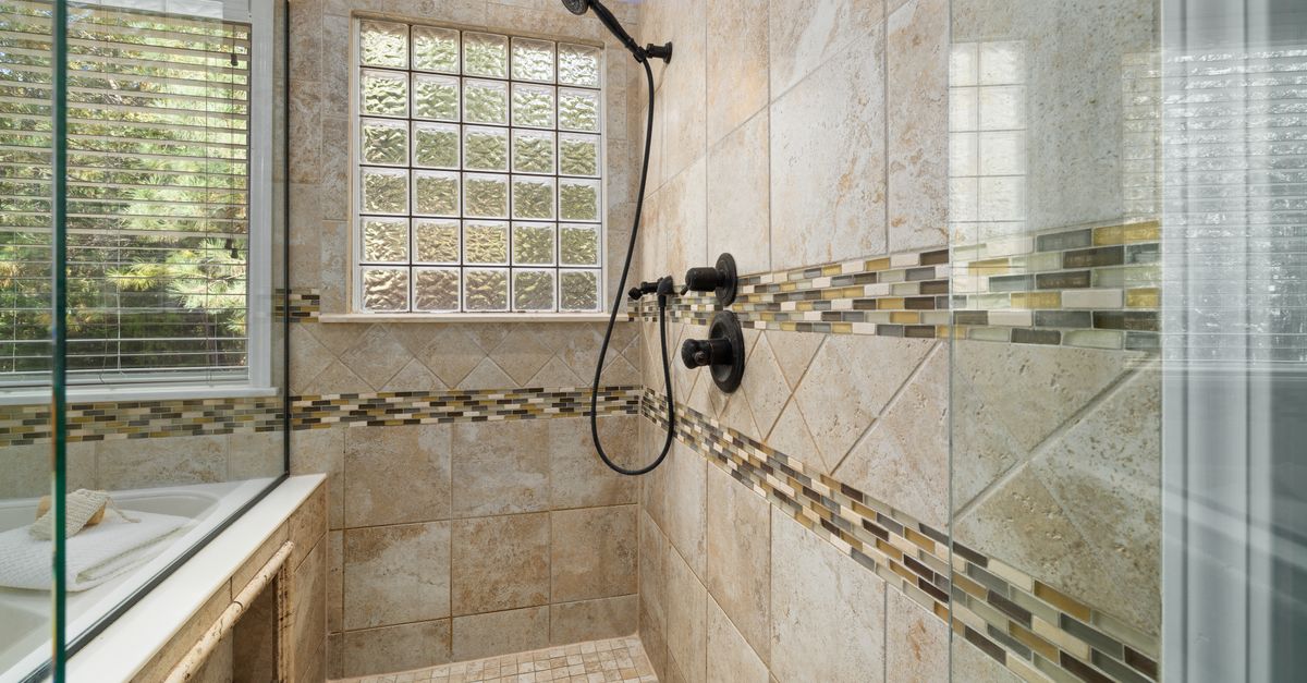 Modern bathroom with tiled shower, glass bricks, and natural light.