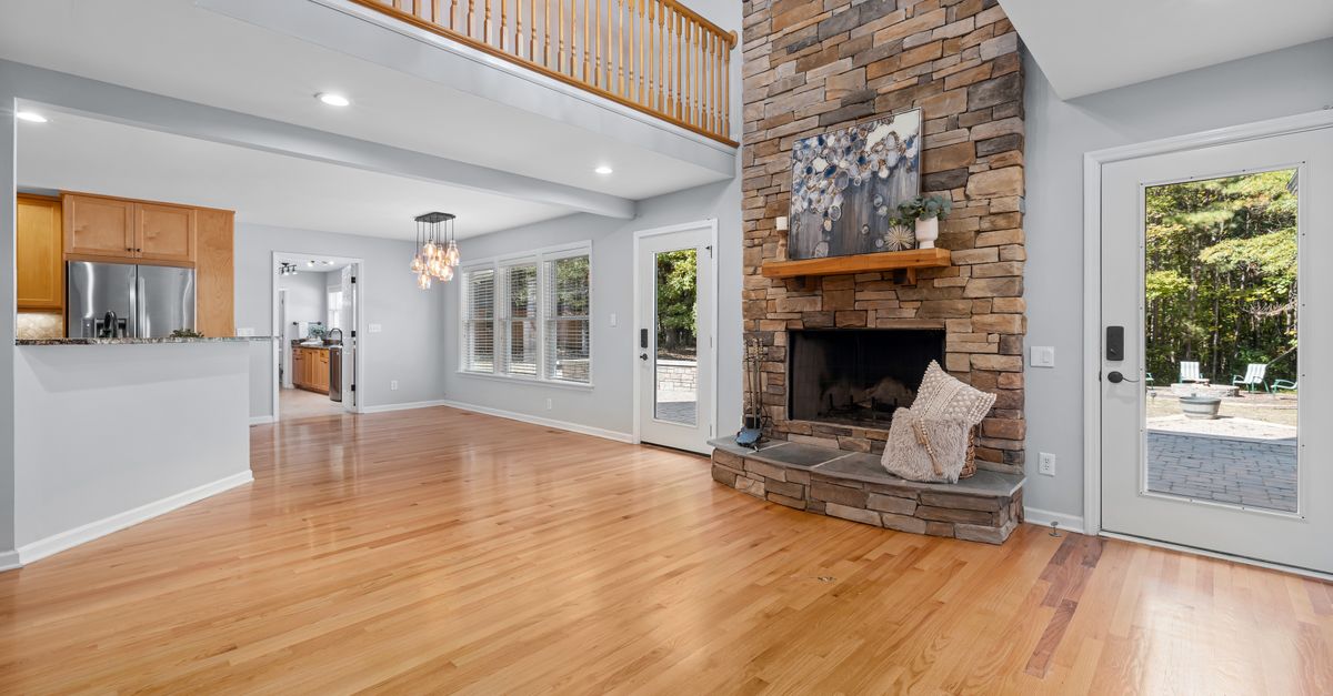 Bright and spacious living room showcasing a modern stone fireplace and high ceilings.