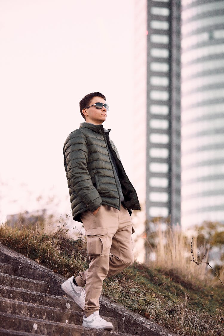 Young Man In A Casual Trendy Outfit Walking Down Steps In City 