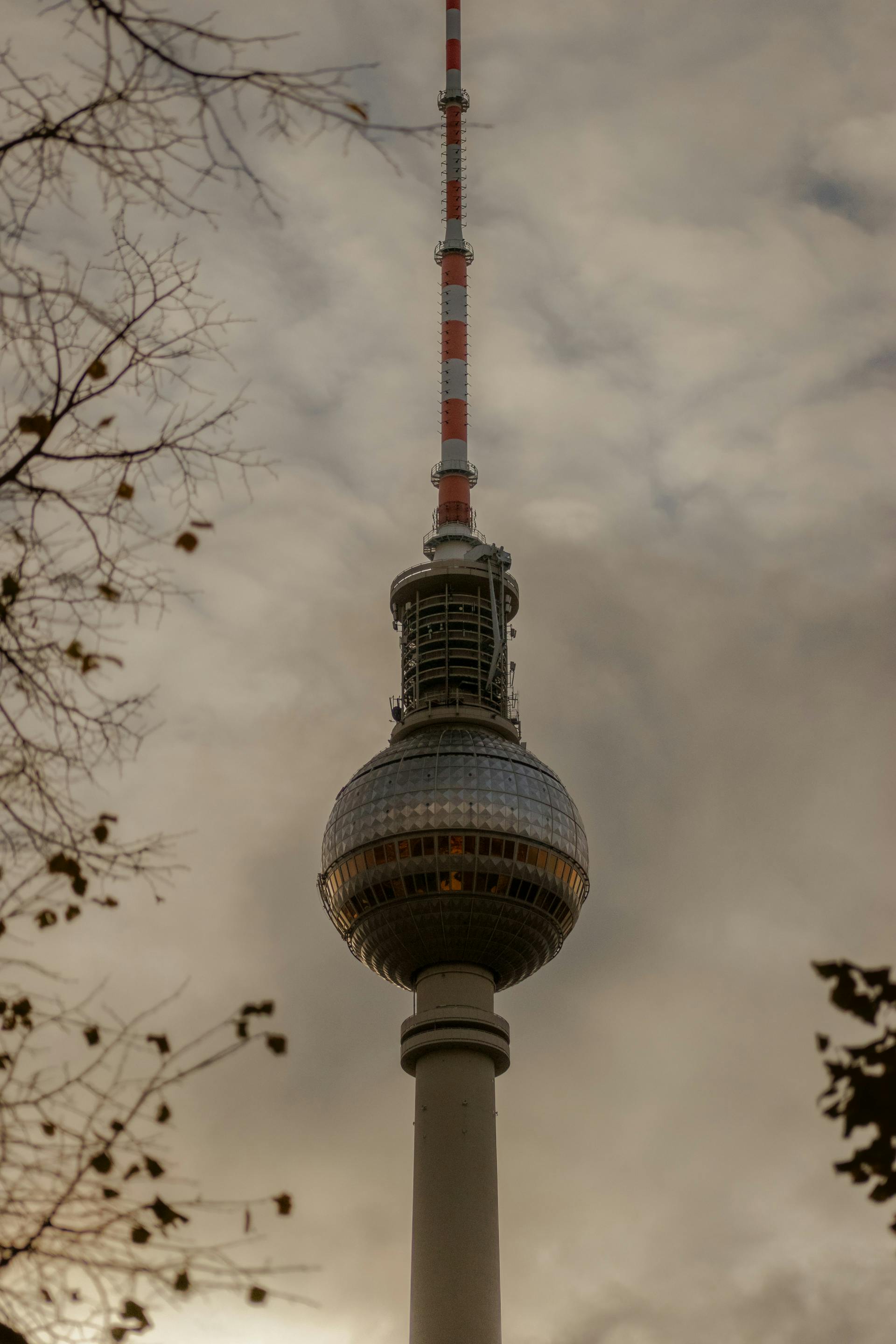 Close-up view of Berlin's Fernsehturm Tower with a dramatic cloudy sky.