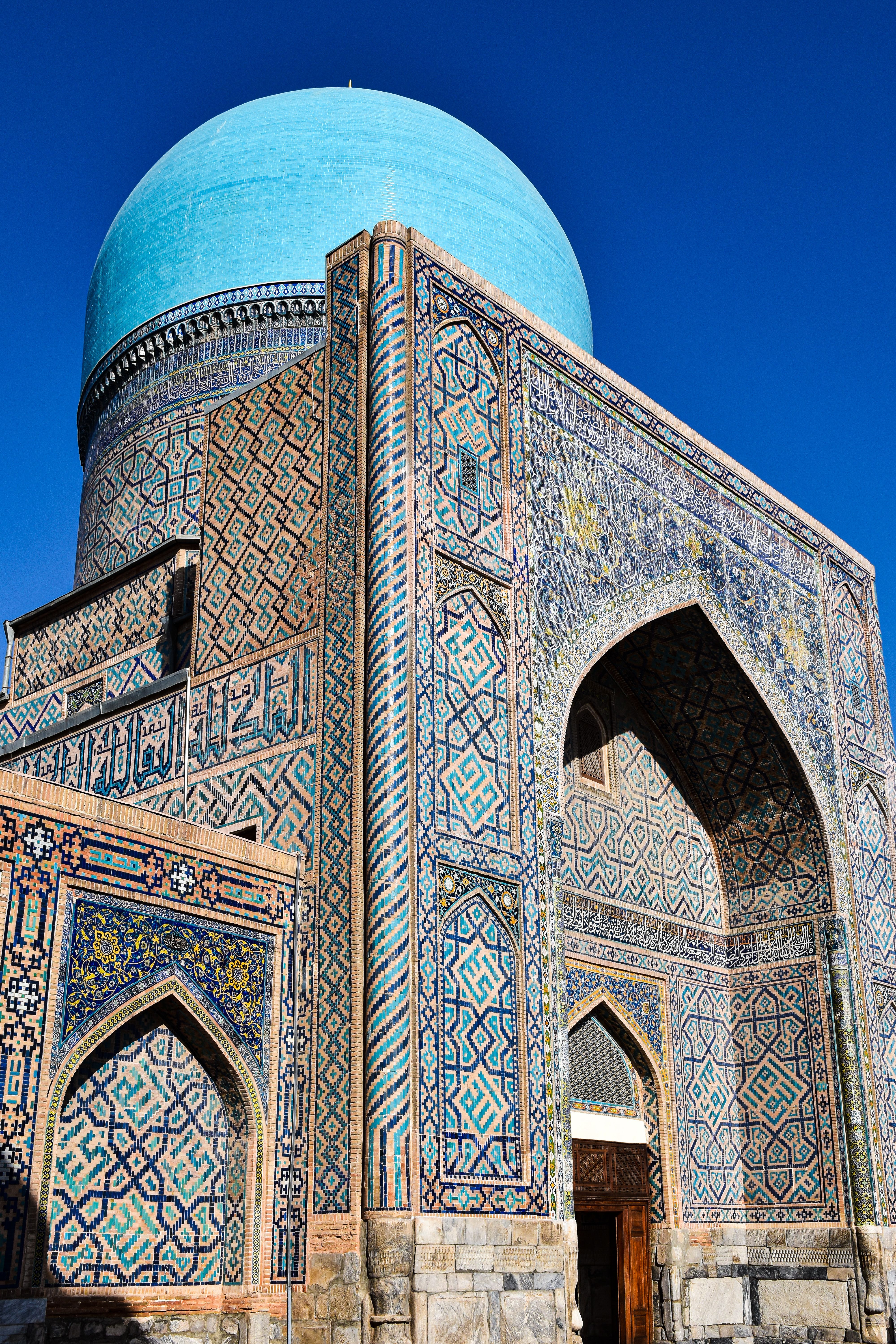Vibrant mosaic facade and blue dome of Tillya Kari Madrassah in Samarkand, Uzbekistan.
