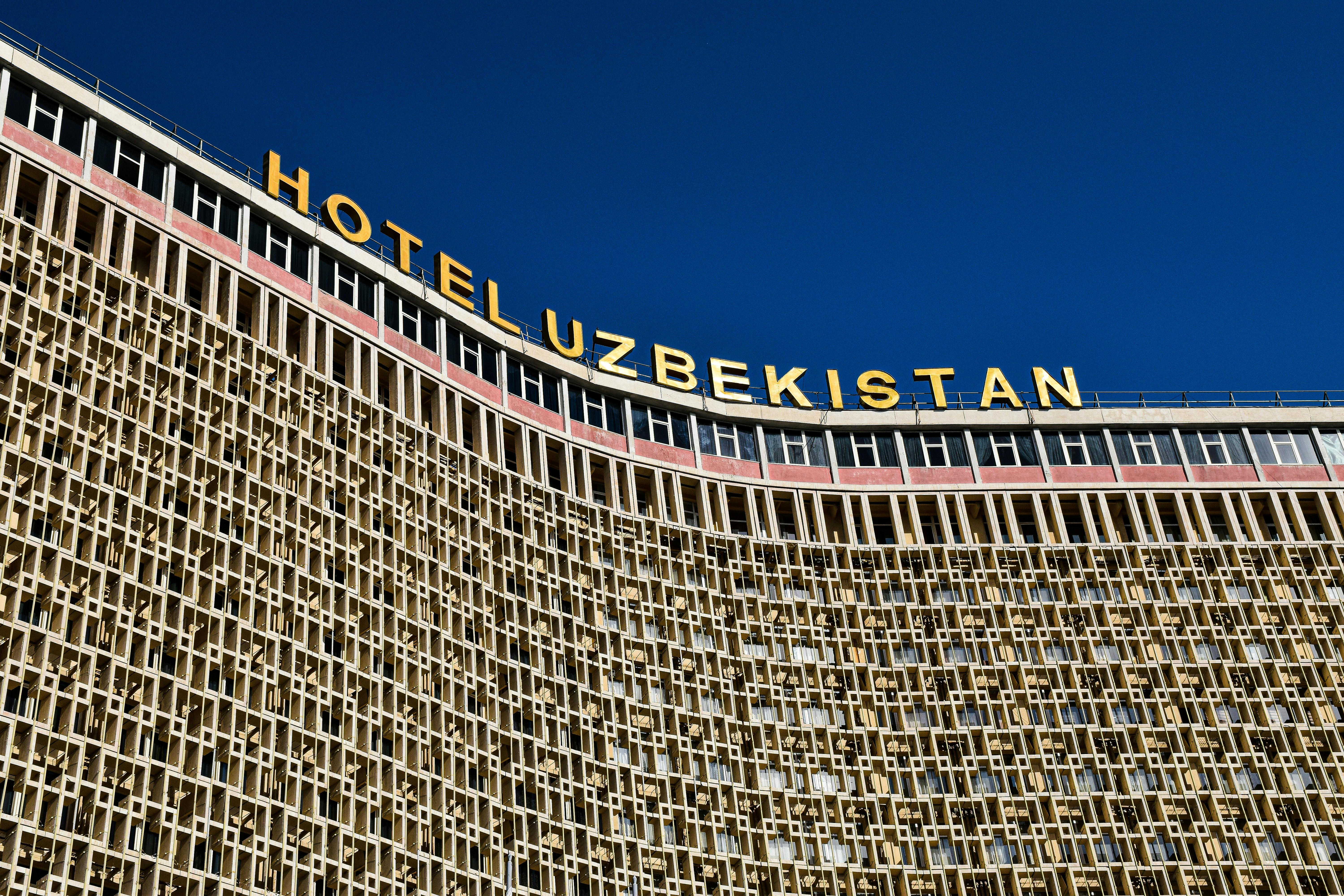 Low angle shot of Hotel Uzbekistan facade against a clear blue sky.