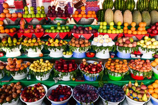 Vibrant assortment of fresh fruits neatly arranged at a market stall, showcasing variety and abundance.