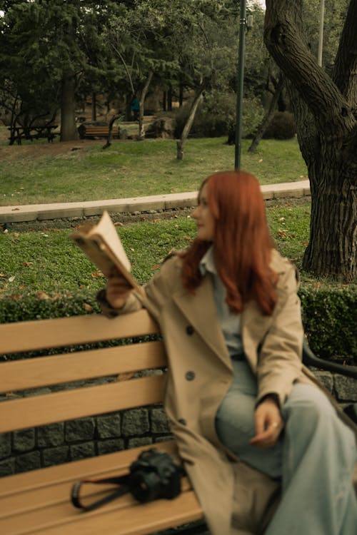 Woman Sitting with Book on Bench in Park