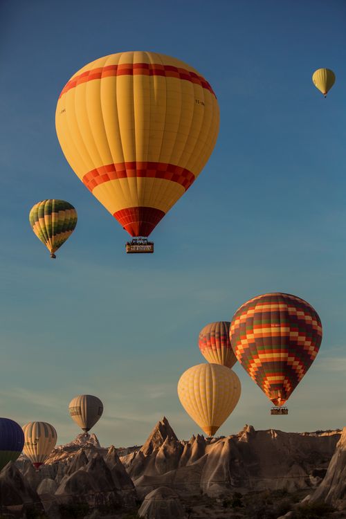 Free Colorful hot air balloons floating over Cappadocia's unique rock formations at sunrise, depicting a serene travel adventure. Stock Photo