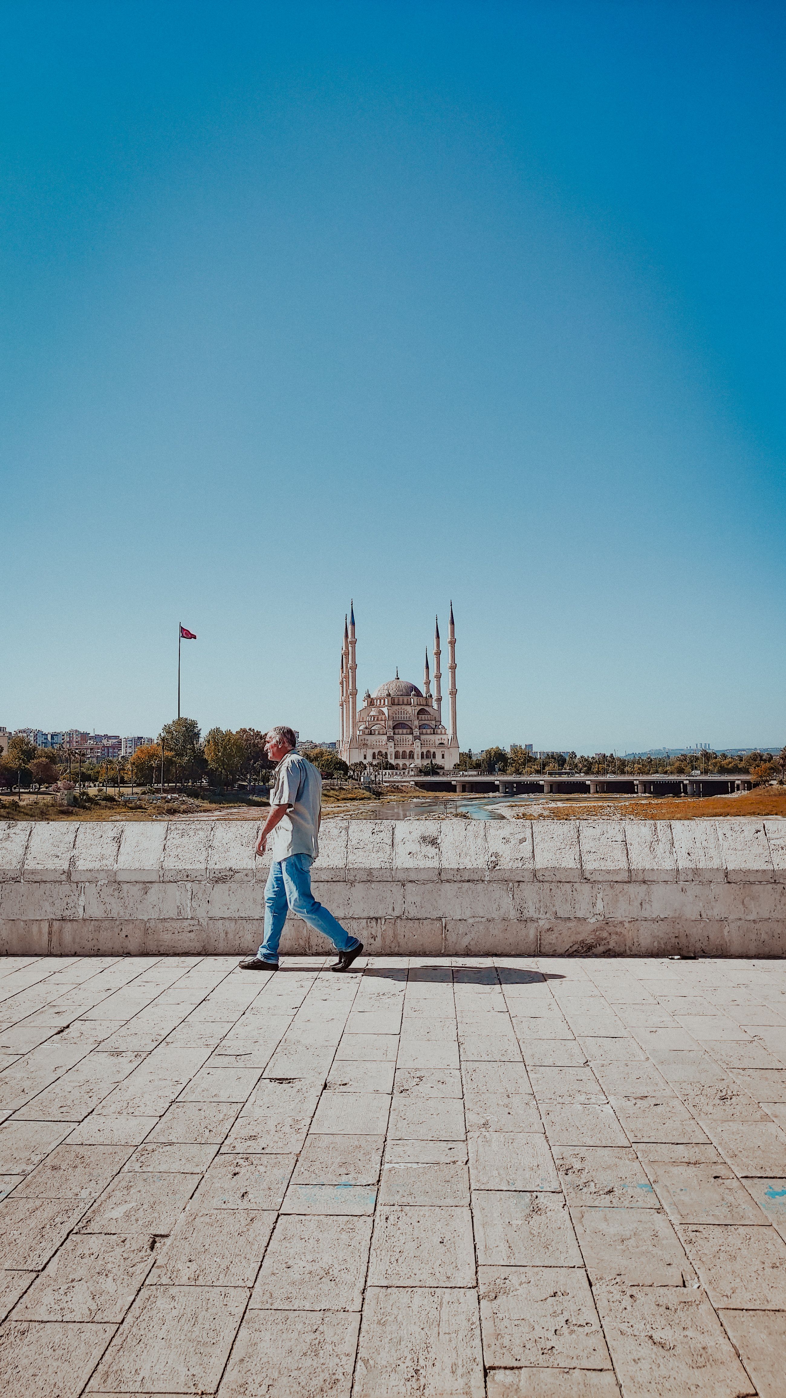 Man Walking on Pavement with Mosque behind · Free Stock Photo