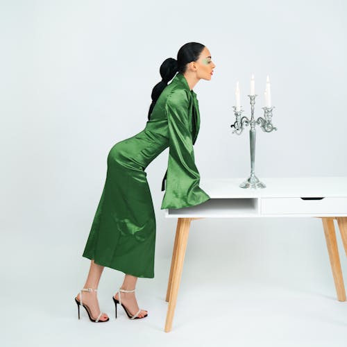 Woman in Green Dress Leaning on Table with Candlestick