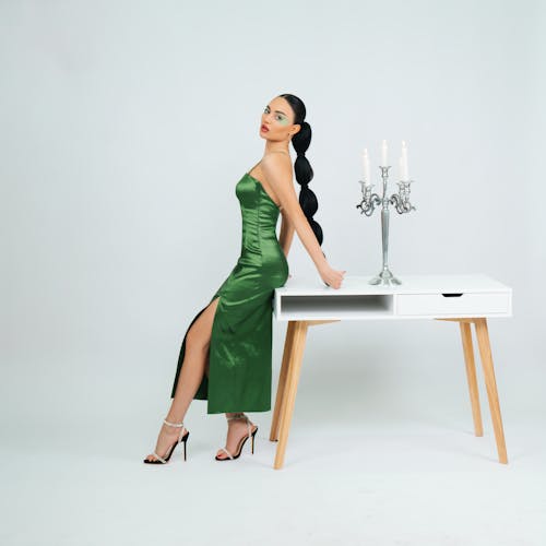 Woman in Green Dress Standing by Table with Candlestick