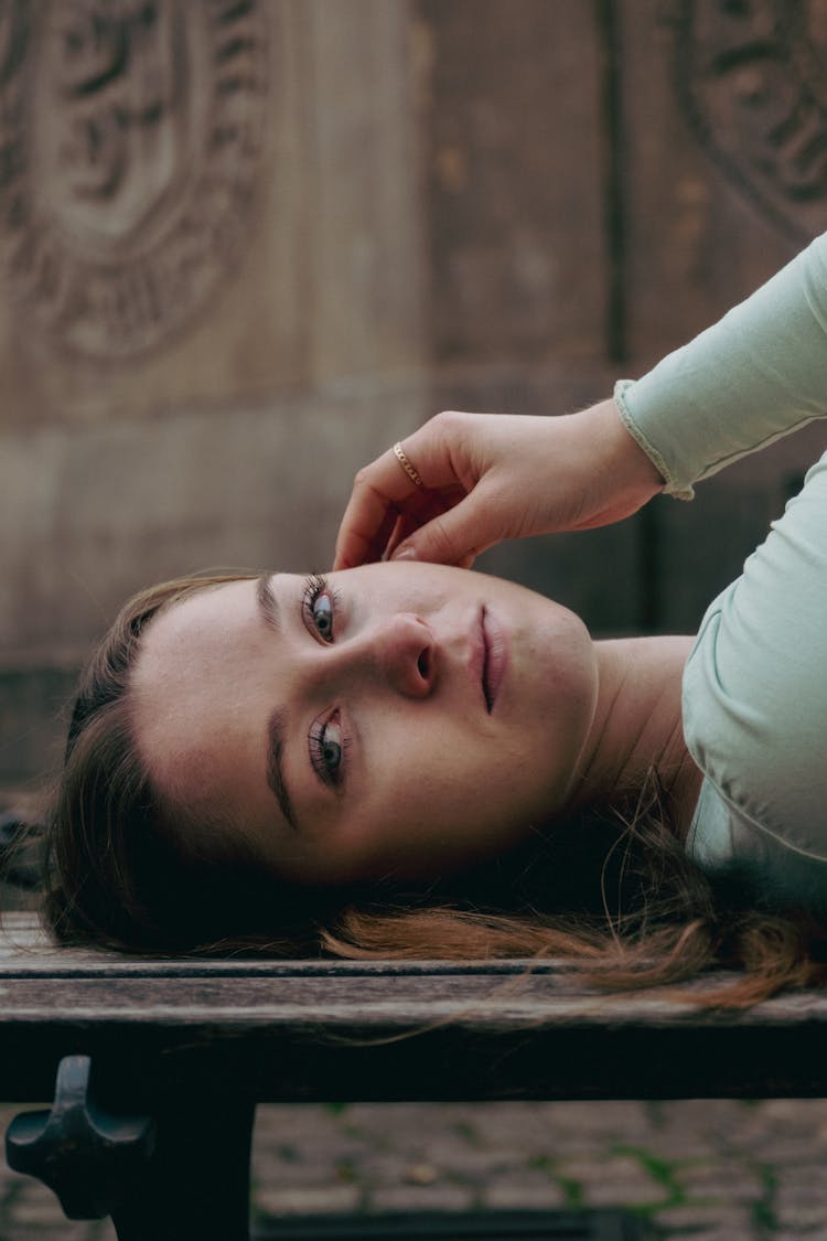 Young Woman Lying On Bench On Street