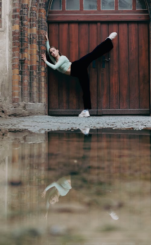 Young Woman Stretching in Front of a Wooden Gate