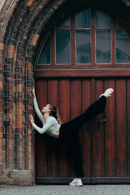 Woman Stretching in the Gate of an Old Building