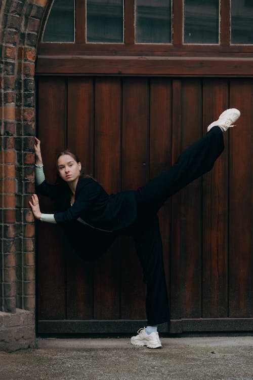 Woman Stretching with Leg Raised by Building Wall