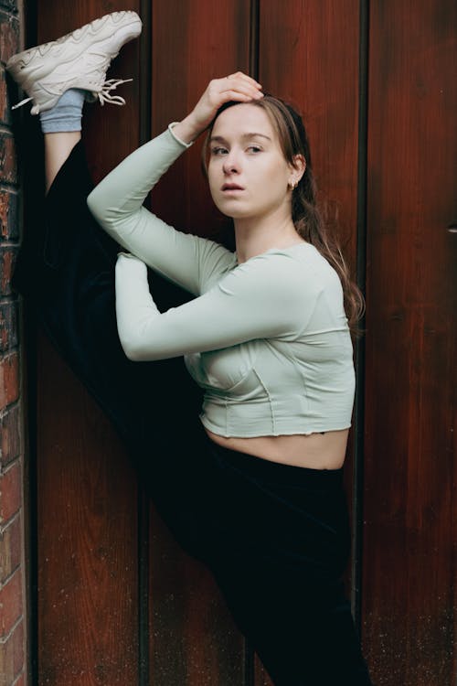 Young Woman in Sportswear Stretching near Wall