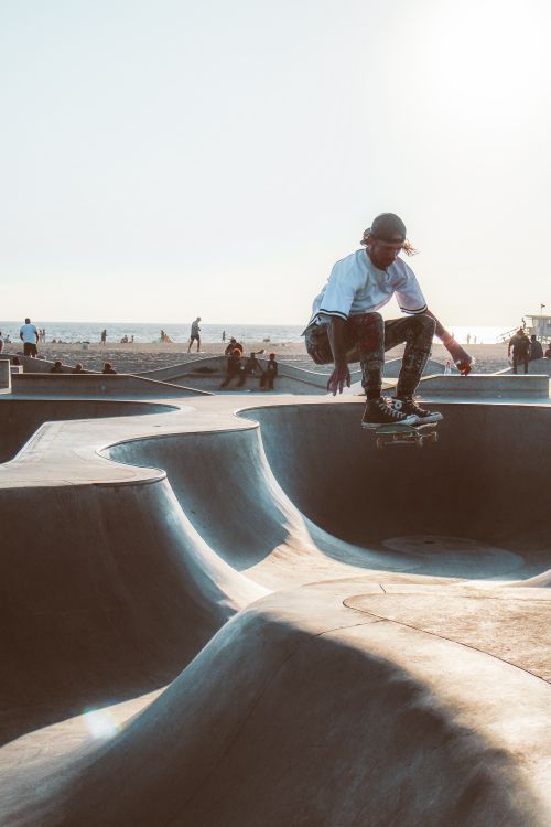 Free Dynamic action shot of a skateboarder mid-air at Venice Beach skatepark, Los Angeles. Stock Photo