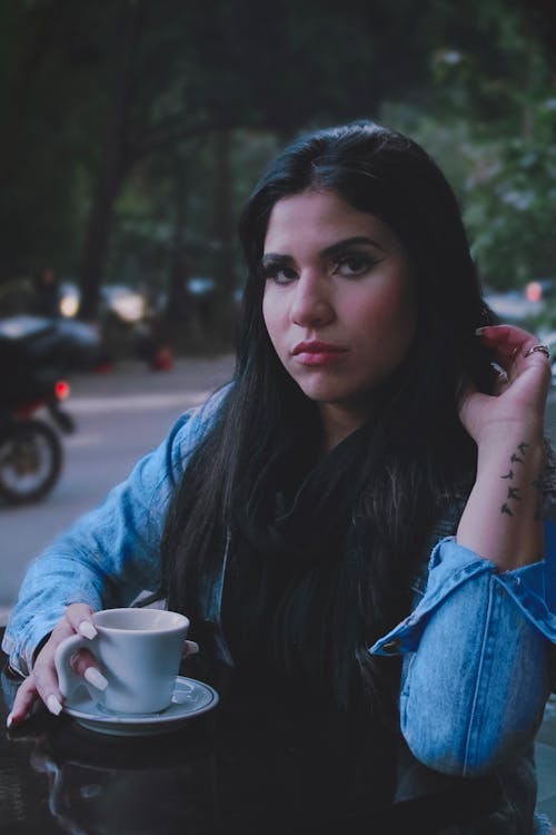 Free Young Woman Sitting at the Table with a Cup of Coffee  Stock Photo