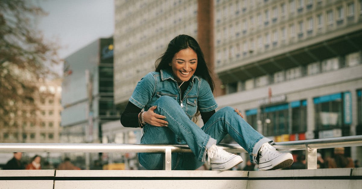 Young Woman in a Denim Outfit Sitting Outside in City and Smiling ...