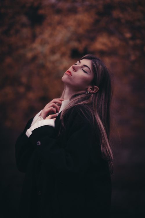 Free A young woman posing elegantly with eyes closed in an autumnal Berlin setting. Stock Photo