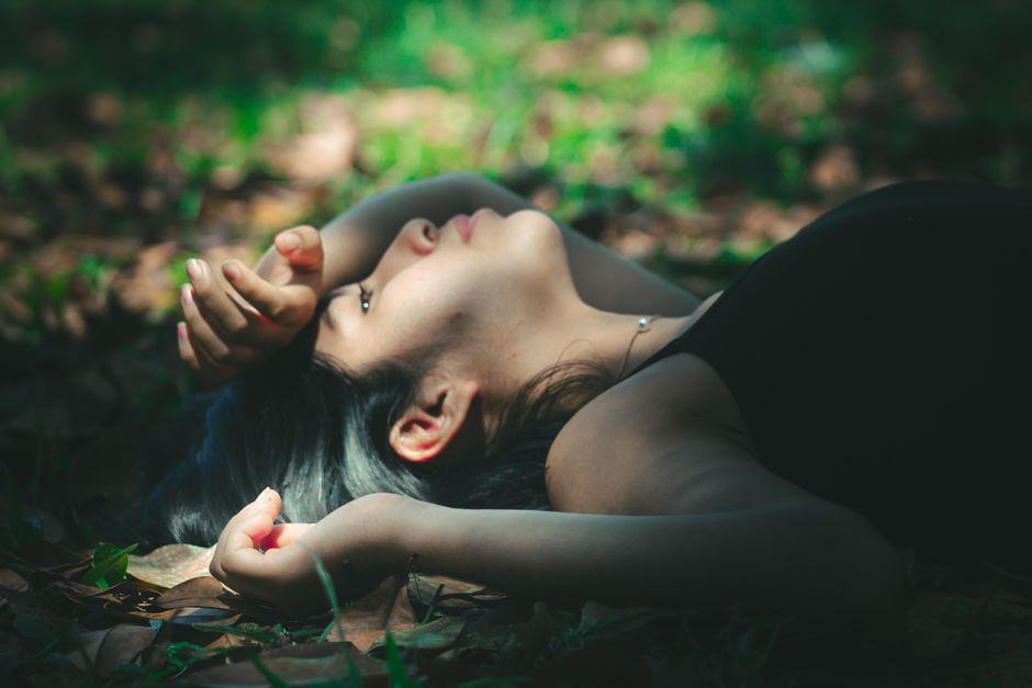A young woman lies in a meadow, enjoying the serenity of a sunny day.