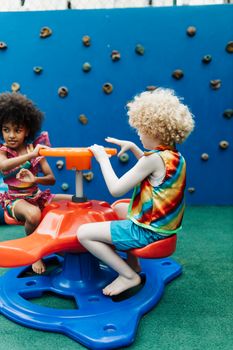 Two children enjoying a colorful carousel ride in an outdoor playground.