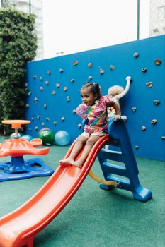 A happy child enjoys sliding down a colorful playground slide outdoors.